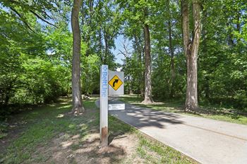 A sign on a post in a wooded area with a yellow arrow pointing to the right.